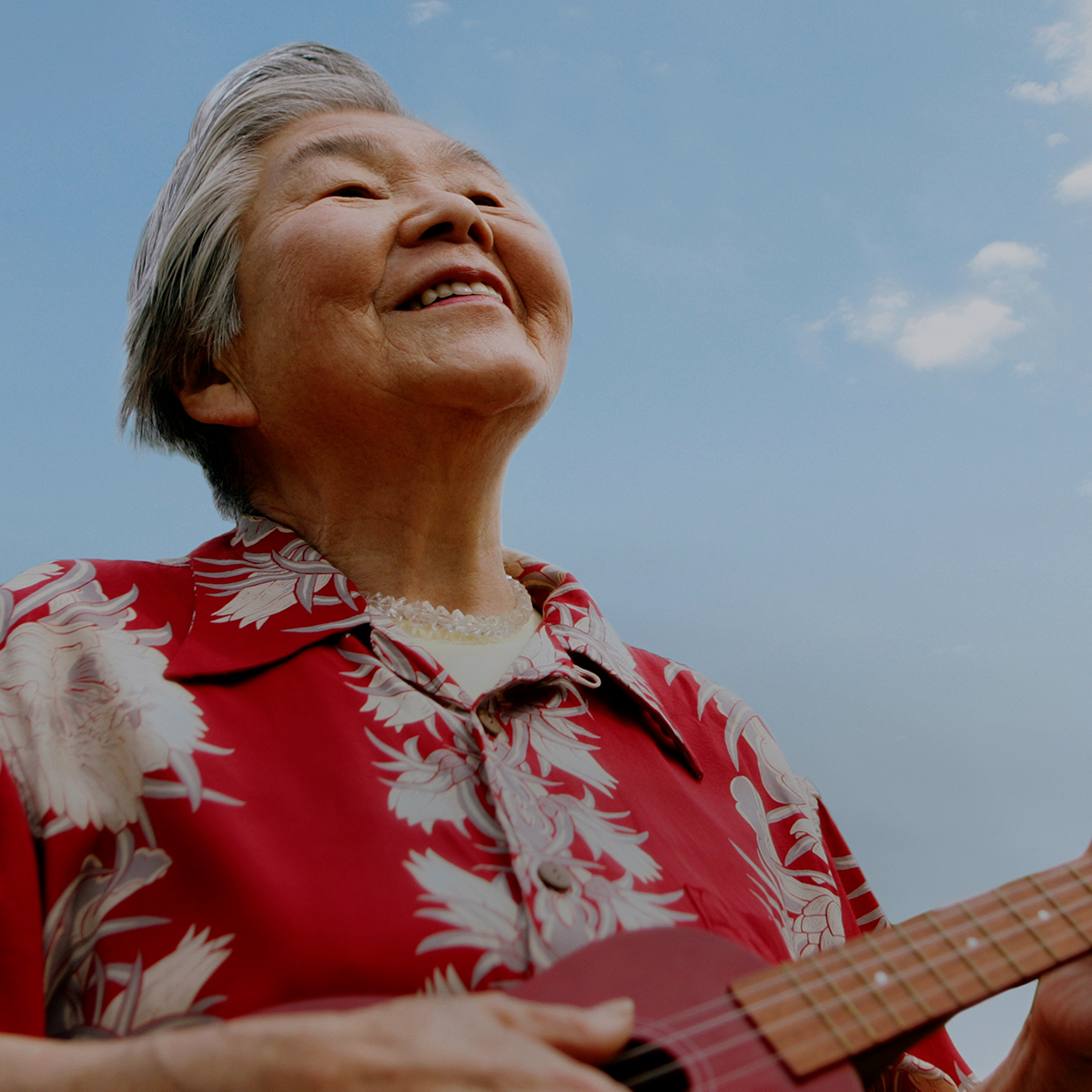a person smiling and playing a ukelele